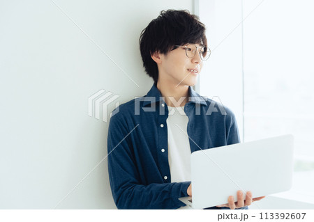 パソコンを操作するメガネの若い男性 113392607