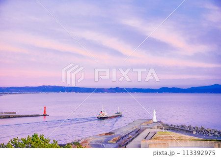 【静岡県】ピンク色に染まった夕焼け空の下、田子の浦港を出港する船舶 113392975