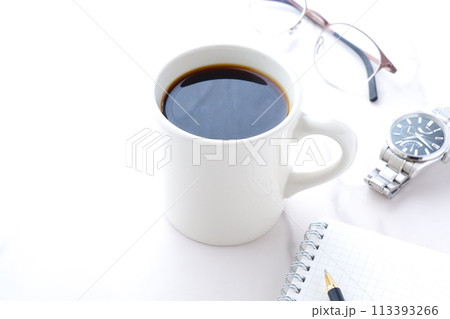 コーヒーを飲みながら、リング式のメモ帳とペンでデスクワークをしているイメージ 113393266