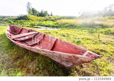 Abandoned red wooden fishing boat at the lake in summer day Abandoned red wooden fishing boat at the lake in summer day 113394969
