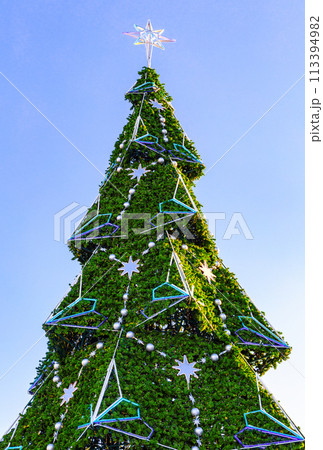 Large plastic decorated Christmas tree with balls against the blue sky 113394982