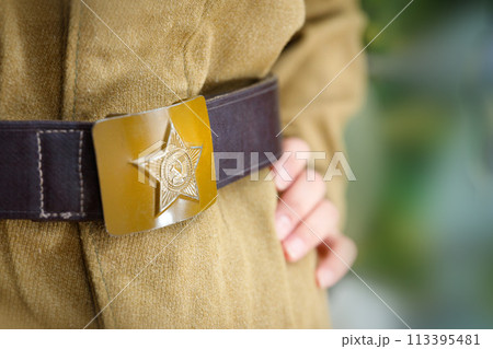 Vintage buckle with the image of a star, hammer and sickle from the Great Patriotic War, worn on a khaki military uniform. 113395481