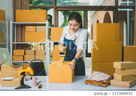 Startup small business owners holding packing machine and sealing cardboard boxes with tape to deliver products to customers- concept shopping online 113399032