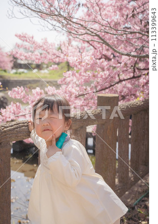 桜をバックにウインクする女の子 113399643