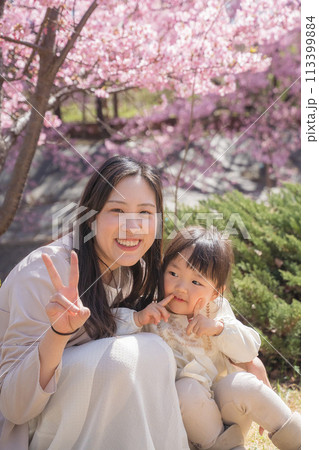 桜の咲く公園で遊ぶ母と娘 113399884