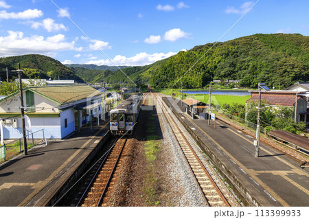 青空の下の西佐川駅に迫るするキハ系列車 113399933