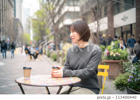 東京丸の内でウインドウショッピング中にコーヒーブレイクする女性 東京丸の内でウインドウショッピング中にコーヒーブレイクする女性 113400440