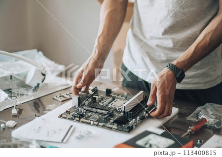 Tech Tinkerer : Amidst an array of electronic parts, a craftsman engages in the delicate task of computer maintenance 113400815