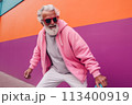 Smiling happy cool gray haired bearded hipster old senior man skater with skateboard in hand on pink background. Older people freedom spirit concept 113400919