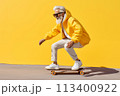 happy cool gray haired bearded hipster old senior man skater with skateboard moves on yellow background. Older people freedom spirit concept 113400922
