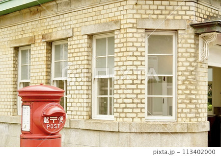 レトロな赤いポストとレンガの建物 113402000