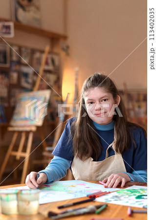 Vertical portrait of smiling teen girl with Williams syndrome looking at camera in art studio 113402035