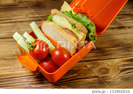 Lunch box with sandwiches and fresh vegetables on a wooden table Lunch box with sandwiches and fresh vegetables on a wooden table 113402610