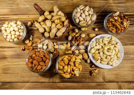 Assortment of nuts on wooden table. Almond, hazelnut, pistachio, peanut, walnut and cashew in small bowls. Top view. Healthy eating concept 113402648