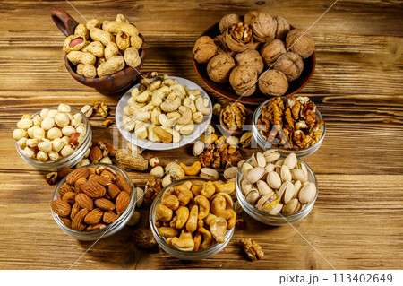 Assortment of nuts on wooden table. Almond, hazelnut, pistachio, peanut, walnut and cashew in small bowls. Healthy eating concept 113402649