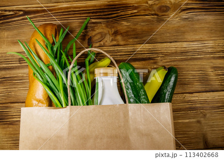 Paper bag with different food on wooden table. Top view. Grocery shopping concept Paper bag with different food on wooden table. Top view. Grocery shopping concept 113402668