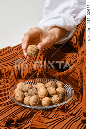 Unrecognizable woman placed a plate of walnuts on the hem of her skirt 113402688