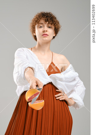 Young woman cuts grapefruit on the fly 113402699