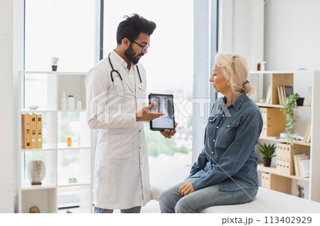 Bearded male in lab coat holding tablet with MRI scan. Bearded male in lab coat holding tablet with MRI scan. 113402929
