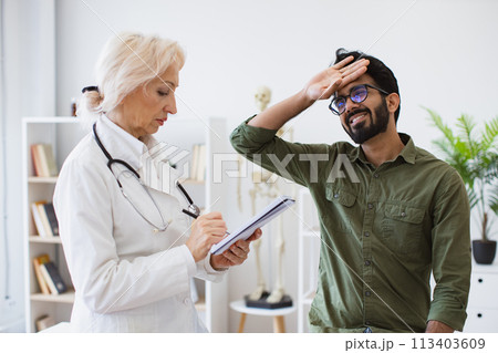 Elder physician giving recommendations and writing prescription. 113403609