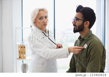 Serious bearded man visiting family doctor for examination in general practice. Serious bearded man visiting family doctor for examination in general practice. 113403619