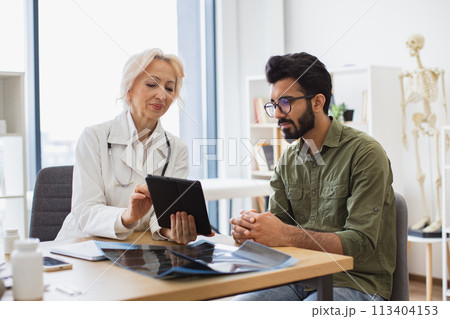 Young gentleman describing symptoms of illness to female doctor. 113404153