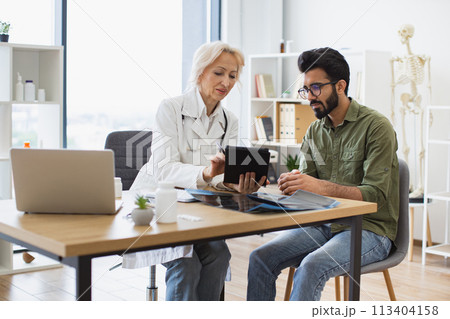 Mature specialist reading out electronic instruction for taking medication. 113404158