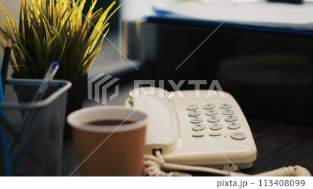Cup of coffee on office desk next to paperwork containing business financial information income statements, close up shot. Company invoice documents and hot beverage in accounting workspace 113408099