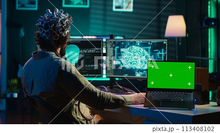 IT admin coding and using EEG headset to upload brain into green screen laptop, gaining immortality. Neuroscientist engineering transhumanism experiment on chroma key device, camera A IT admin coding and using EEG headset to upload brain into green screen laptop, gaining immortality. Neuroscientist engineering transhumanism experiment on chroma key device, camera A 113408102