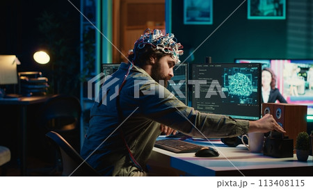 Engineer with EEG headset inserting cartridge into PC to use high tech software allowing for brain transfer into virtual world. Man putting disk in computer to start consciousness upload, camera A 113408115
