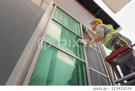 Construction worker repairing the sliding window. Open cap of adjust rail wheel. 113410224