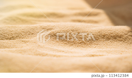 Yellow clean sand with wavy patterns under sunlight Yellow clean sand with wavy patterns under sunlight 113412384