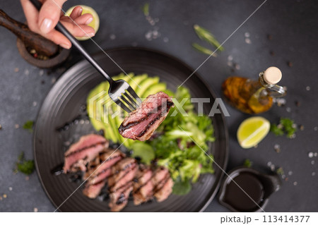 grilled cooked piece of tuna fillet with sliced avocado and salad on black ceramic plate grilled cooked piece of tuna fillet with sliced avocado and salad on black ceramic plate 113414377