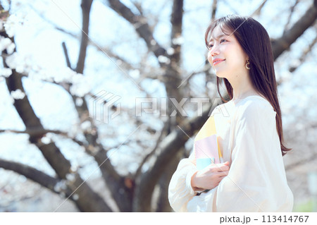 桜並木の河川敷を歩く女性 113414767