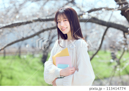 桜並木の河川敷を歩く女性 113414774