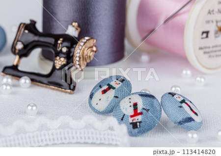 still life of a skein of thread for sewing, needles, buttons, sewing machine on a white background 113414820