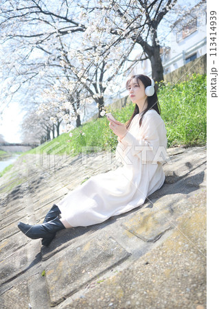 桜の下で音楽を聴く女性 113414939