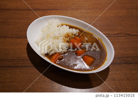 Japanese curry with rice in a white plate on a wooden table Japanese curry with rice in a white plate on a wooden table 113415018