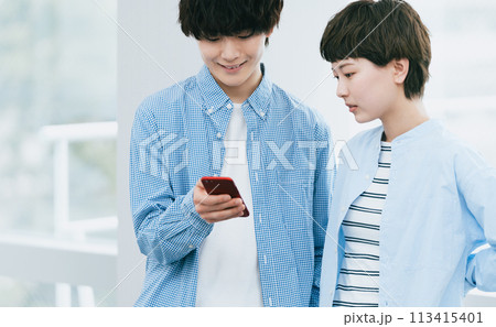 スマホを見る若い男女 スマホを見る若い男女 113415401