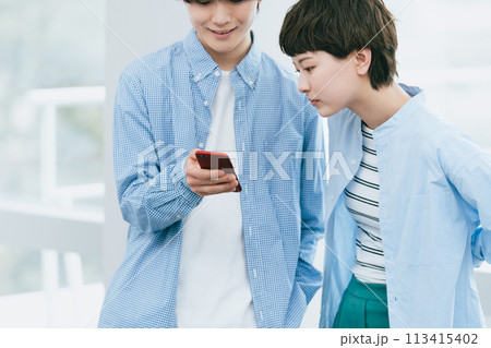 スマホを見る若い男女 113415402