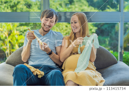 In a heartwarming scene, the future mom and dad hold their unborn baby's clothes in their hands, savoring the joy of anticipation and shared excitement for their little one's arrival 113415734