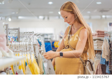 Expectant mother joyfully selects adorable clothes for her unborn baby while enjoying a shopping spree in the vibrant aisles of the shopping center Expectant mother joyfully selects adorable clothes for her unborn baby while enjoying a shopping spree in the vibrant aisles of the shopping center 113415767
