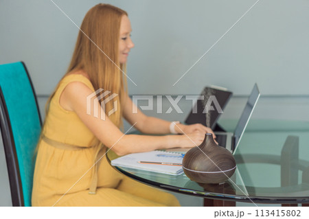 Expectant woman enhances work environment, using an aroma diffuser for a soothing atmosphere during pregnancy Expectant woman enhances work environment, using an aroma diffuser for a soothing atmosphere during pregnancy 113415802