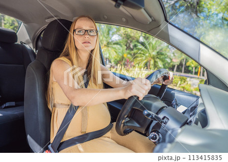 Pregnant woman driving with safety belt on in the car. Confident and capable, a pregnant woman takes the wheel, driving with care and determination as she navigates the journey of motherhood Pregnant woman driving with safety belt on in the car. Confident and capable, a pregnant woman takes the wheel, driving with care and determination as she navigates the journey of motherhood 113415835
