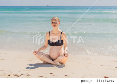 Harmonizing mind and body, a pregnant woman gracefully practices yoga on the beach, embracing the serenity of the seaside for a tranquil and mindful pregnancy experience 113415843