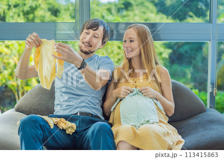 In a heartwarming scene, the future mom and dad hold their unborn baby's clothes in their hands, savoring the joy of anticipation and shared excitement for their little one's arrival In a heartwarming scene, the future mom and dad hold their unborn baby's clothes in their hands, savoring the joy of anticipation and shared excitement for their little one's arrival 113415863