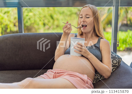 Happy pregnant young woman eating ice cream Happy pregnant young woman eating ice cream 113415870