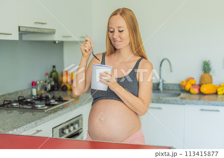 Happy pregnant young woman eating ice cream Happy pregnant young woman eating ice cream 113415877