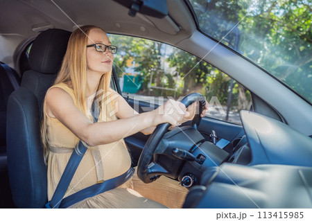 Pregnant woman driving with safety belt on in the car. Confident and capable, a pregnant woman takes the wheel, driving with care and determination as she navigates the journey of motherhood 113415985