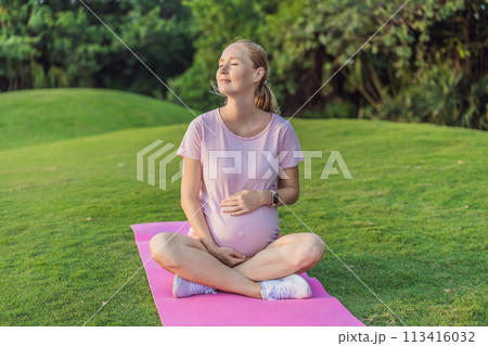 Energetic pregnant woman takes her workout outdoors, using an exercise mat for a refreshing and health-conscious outdoor exercise session 113416032
